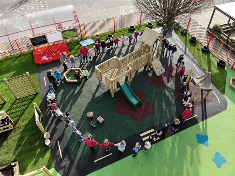 A group of children are circling around a Play Tower that has been installed on a vibrant wetpour surface.