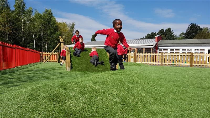 five children running down the climb through tunnel in their playground