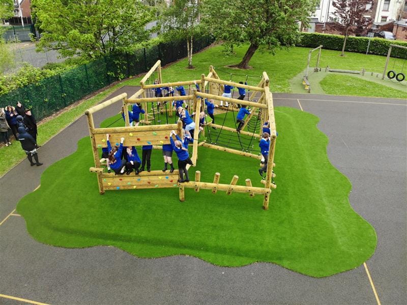 children play on the large timber climbing frame, built on green artificial grass