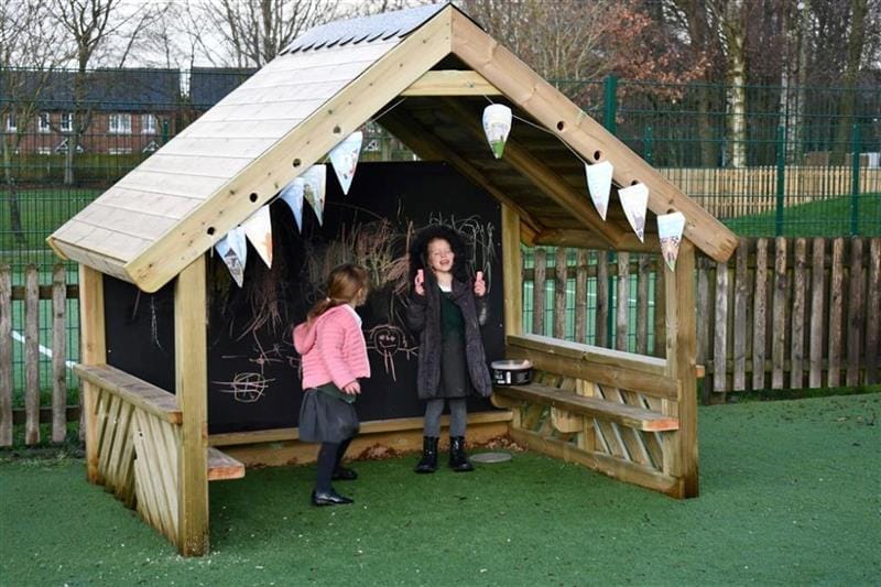 two little girls stand inside the playhouse and play together