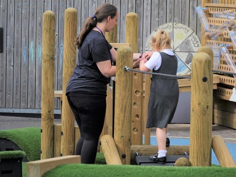 a child stands in between the den-making posts and ties ropes and string between the den-making posts