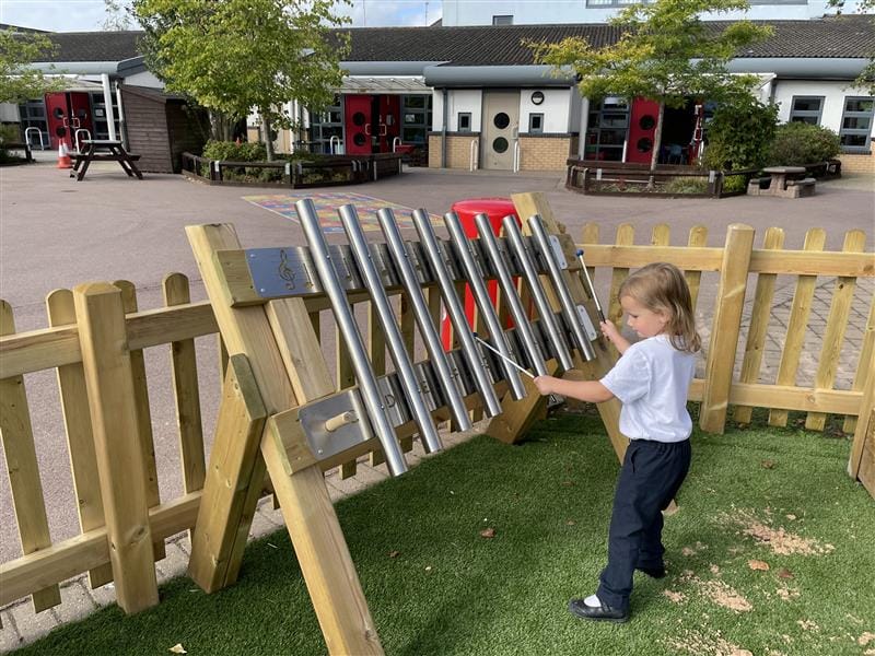 a child stood in front of the freestanding chimes and played with the beater against the chimes