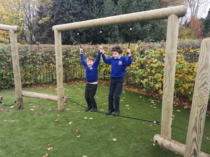 2 children walking across a trim trail tightrope bridge