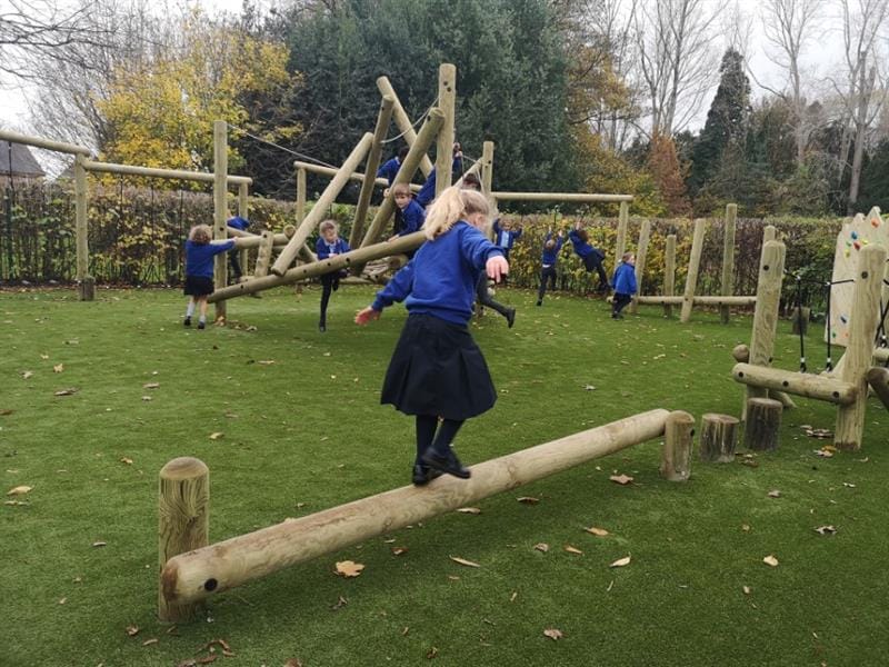 A child balancing on a trim trail balance beam