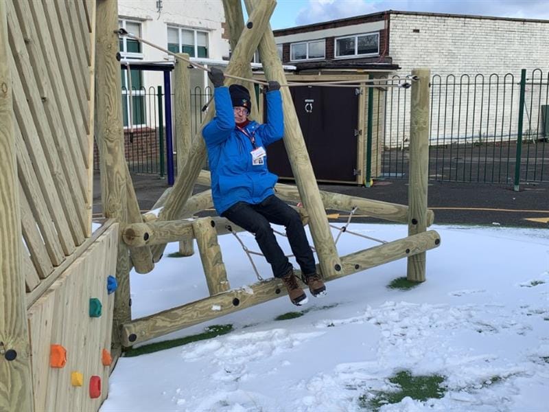 Sam from pentagon play swinging on a climbing frame