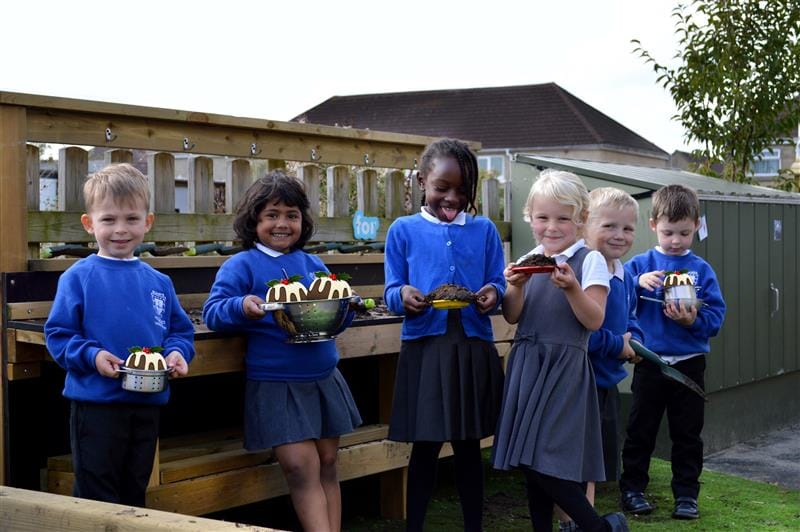 Children stand in front of the mud kitchen and have their picture taken then have chirtsmas puddings super imposed on