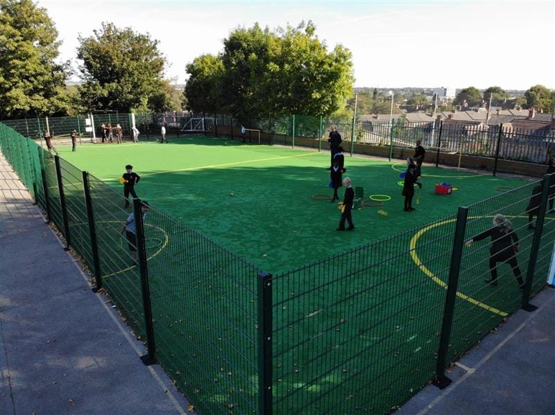 A group of children are playing on a Multi Use Games Area.