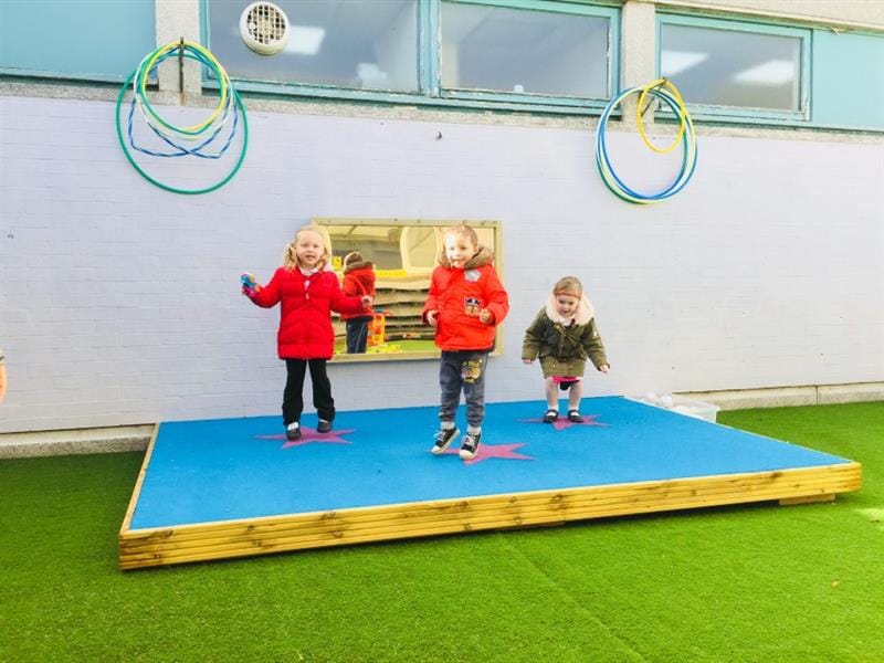 Three children dancing on an outdoor stage for schools
