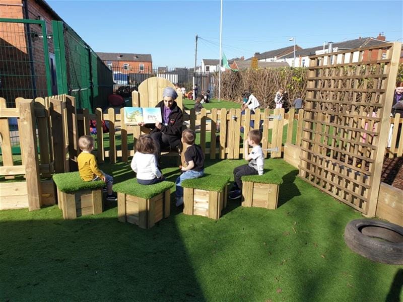 children sit on artificial grass topped seats and reads books