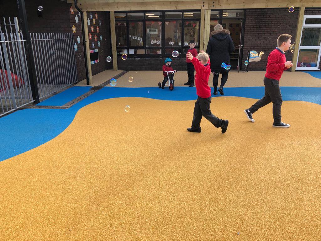 A group of SEN children are chasing bubbles in the playground.