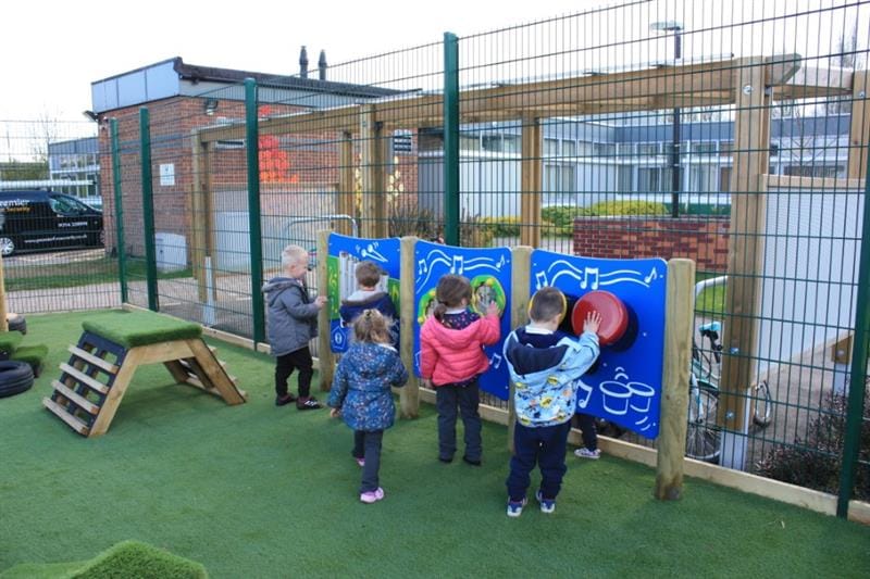 Five children are engaging with musical play equipment and are having fun.