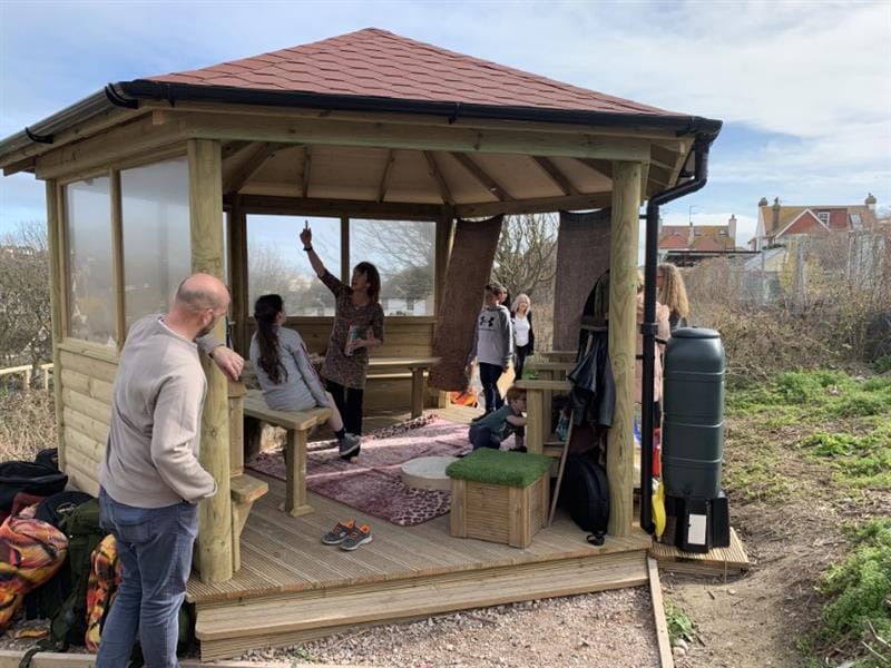 A group of adults are decorating their outdoor classroom with Easter decorations for playground activities.