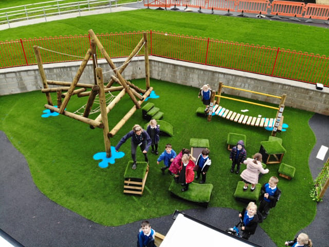A large group of children are playing on their playground, as they group on the Get Set Go blocks and look at the camera smiling.