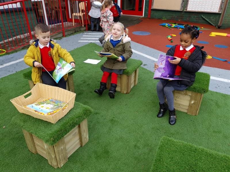 children sit on the grass topped seats and read storybooks