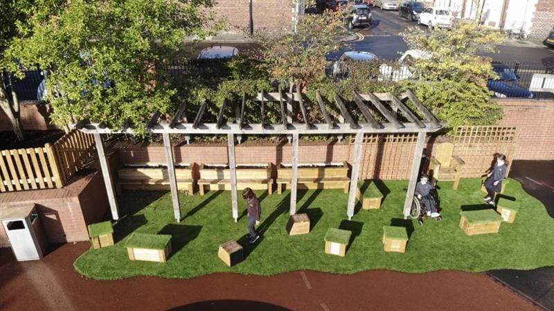 Children walking around artificial grass playground surfacing