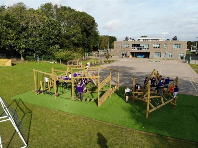 A big group of children climbing along the climbers in their playground, there are 2 climbers for the children to play on 