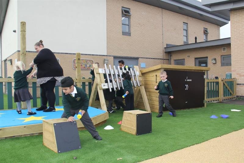 children play music on the drum seat and the large freestanding chimes with a perfomance stage in the background