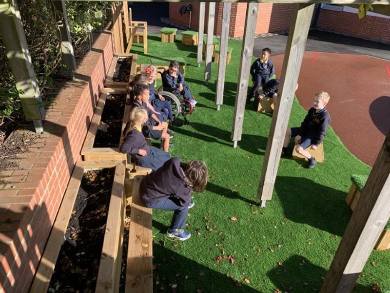 Children sitting on planter benches and artificial grass talking to each other