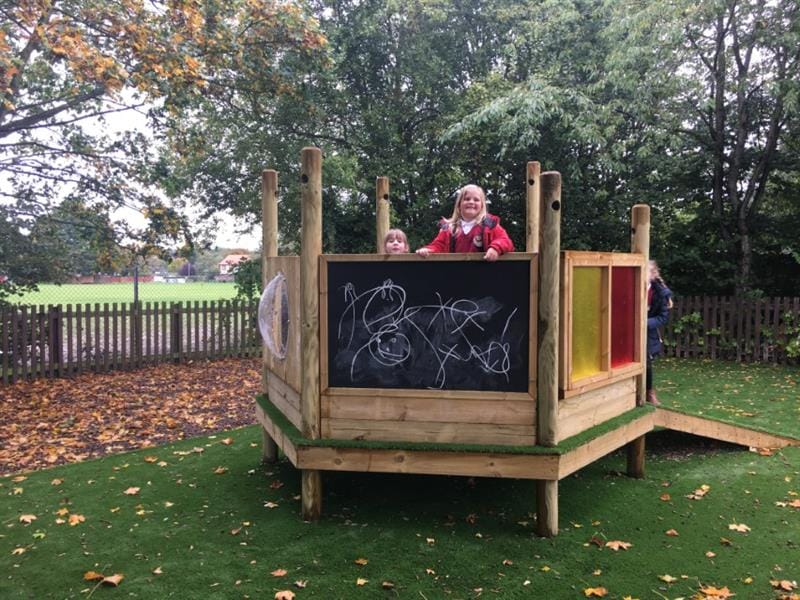 a child stands inside the imagination station and peeks over the top