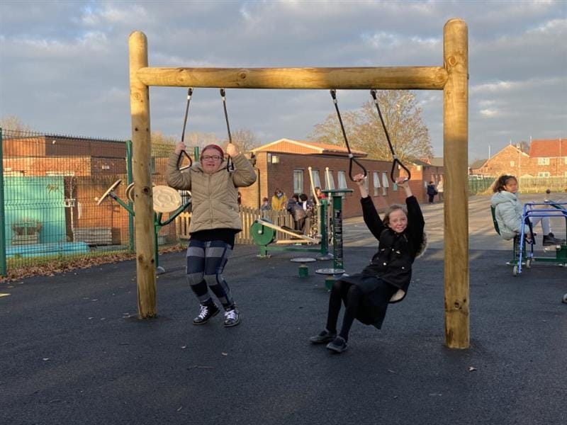 Two children swinging from a heavy work swing on their school playground