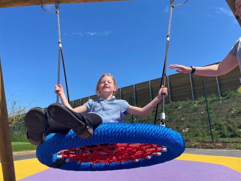  young girl swinging on the chair swing in her playground 