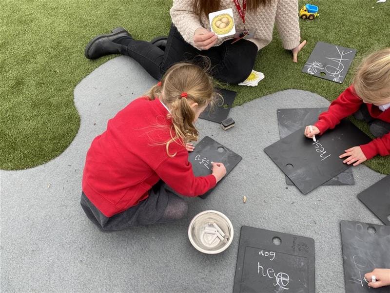 a child sits  on the floor and draws on the scribble board