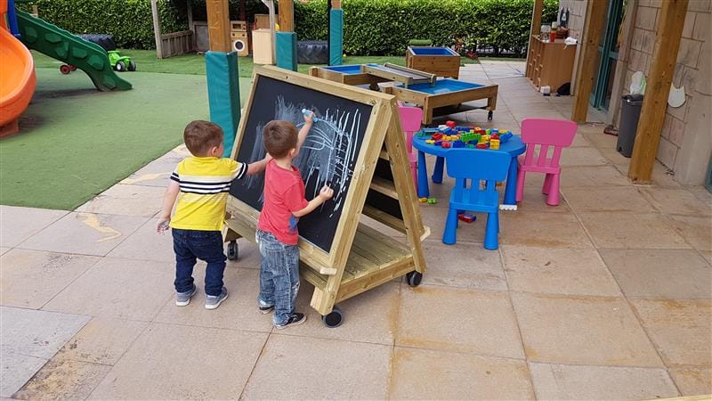 two little boys stand at the easel on wheels and draw on the board