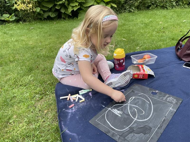 a little girl sits on the floor and draws on the scribble boards
