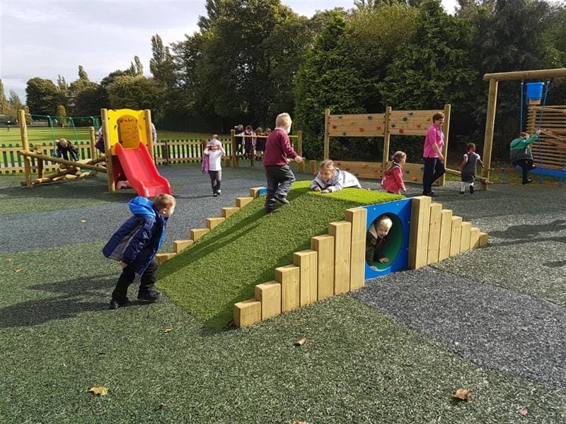 children play on the climb through tunnel hill as one child crawls through beneath