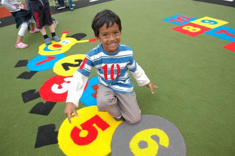 a child kneels on a new playground marking of a caterpillar