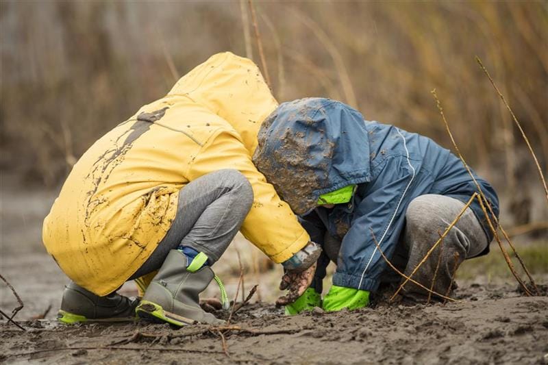 Two children playing in the mud.