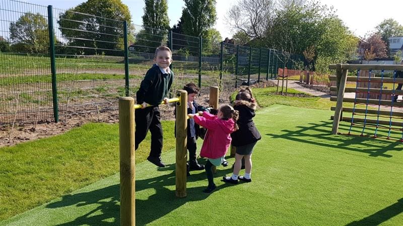 children in rain coats and school uniform play on the rollover bars