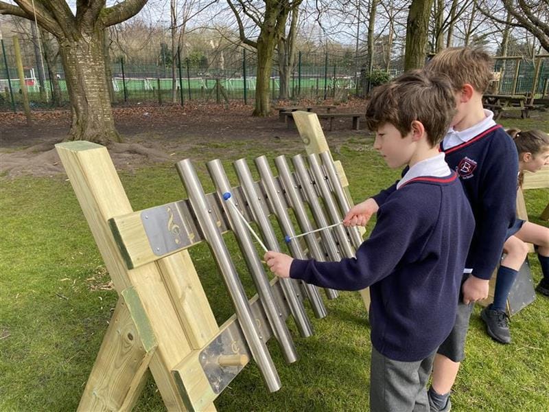 two young boys playing on the musical freestanding chimes