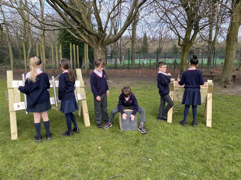 children sit on the drum seats and stand at the other instruments 