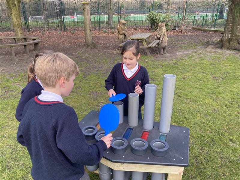 three children stand around the colourful batonka and work together to play a tune