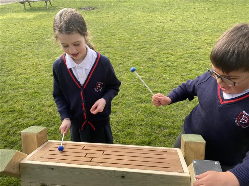 two children play the tongue drum with plastic blue and white beaters