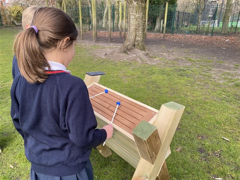 two children work together on playing a drum