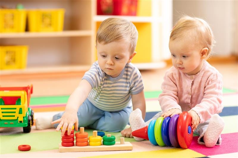 children sit on the play mat and play with colourful baby toys