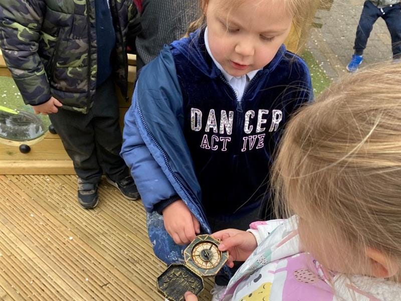 two little girls inspect a plastic compass