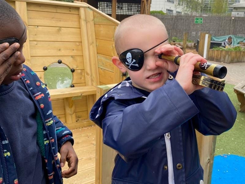 a kid stood with an eye patch and a toy telescope