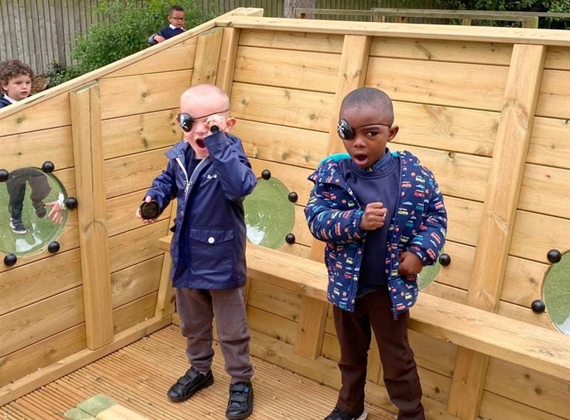 children stand within the timber pirate ship and pretend to be pirates