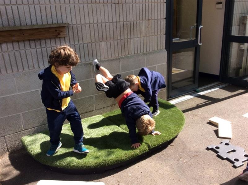 a child performs on the stage and does a handstand whilst his friends stand and watch and try to do the same
