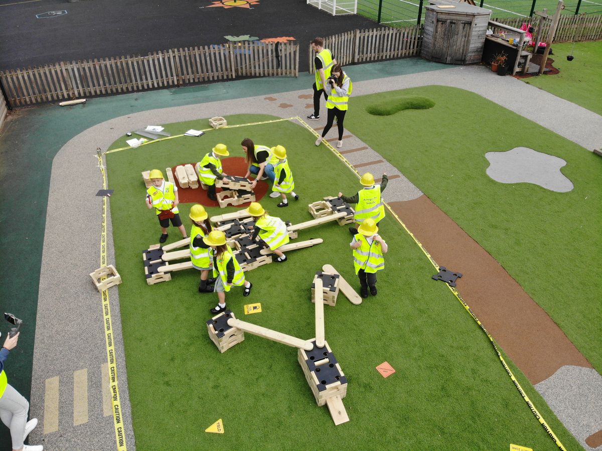 A birds eye view of  the construction blocks in a trail like a plane, the children are around the blocks and putting them together 