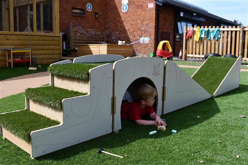 a child lies on the floor under the up and under blocks with some chalk