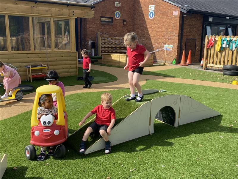 2 young children walking over the up and under blocks, one young boy is sliding down the block