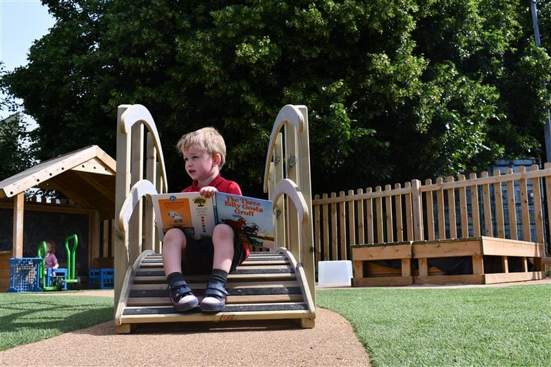 a child sits on the bridge and reads a storybook