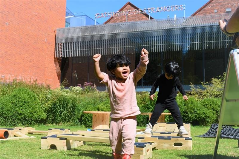 a child cheers as he jumps down from the play builder trail