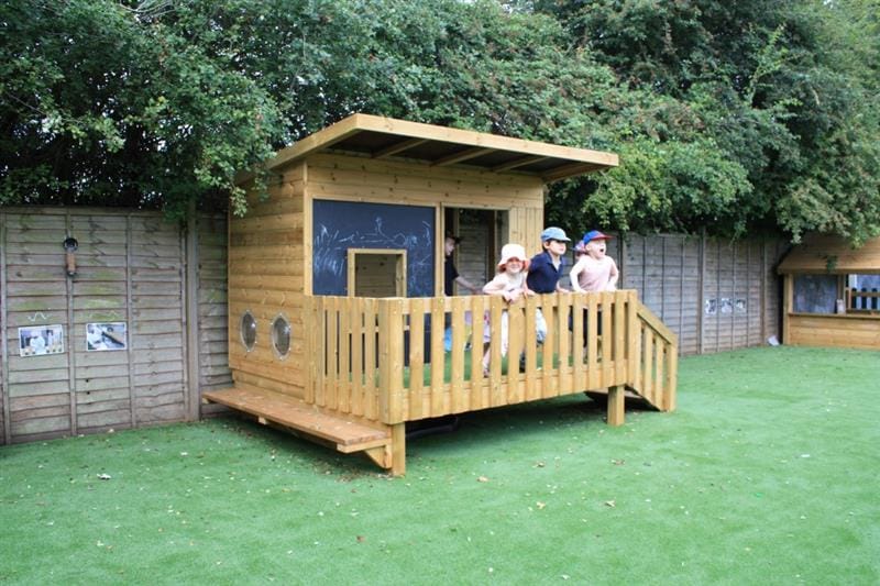 children stand on the decking of the lookout den, looking out at the play space in front of them