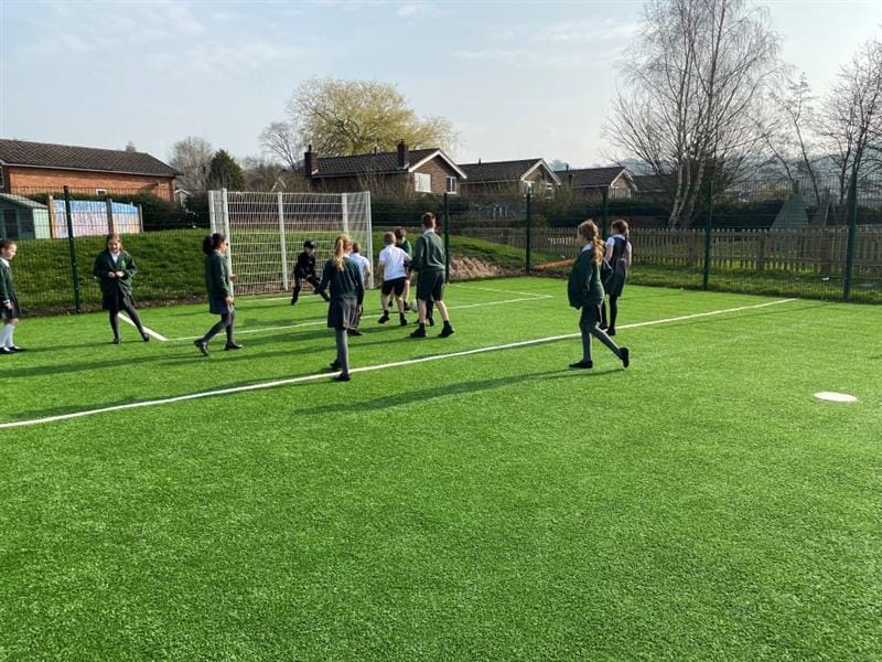 A group of children playing football, they are al chasing after the ball