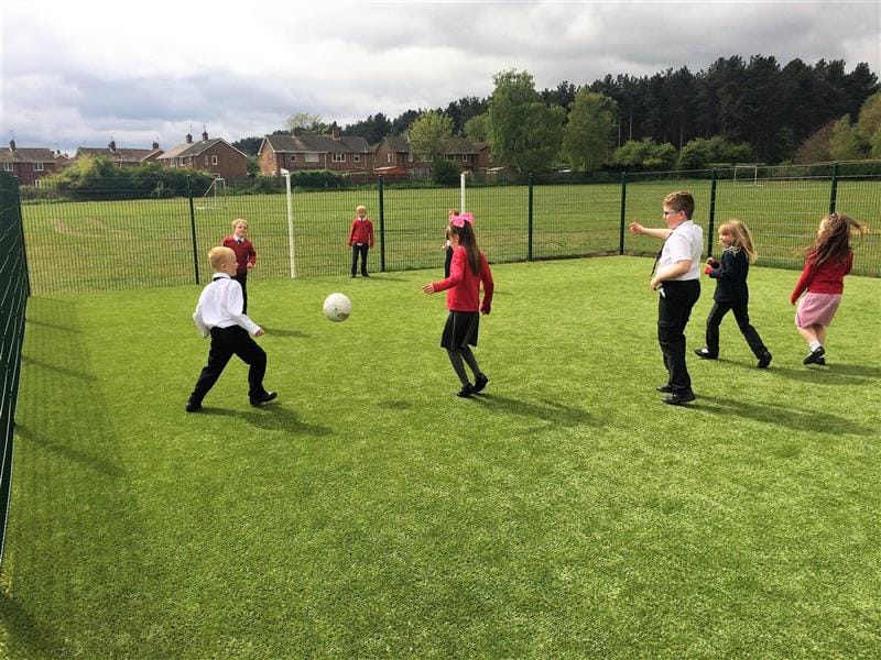 A class of children playing football on the muga 
